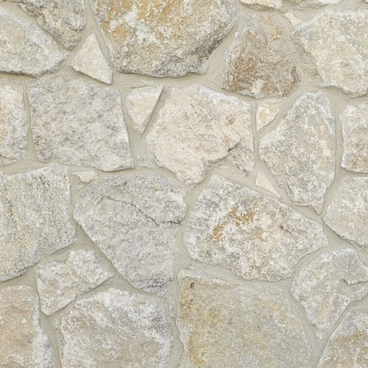 Avelon Stone Cladding features a close-up of irregular, neutral stone pieces set in mortar, creating a rough, textured surface with a free style walling pattern. — Stone Cladding