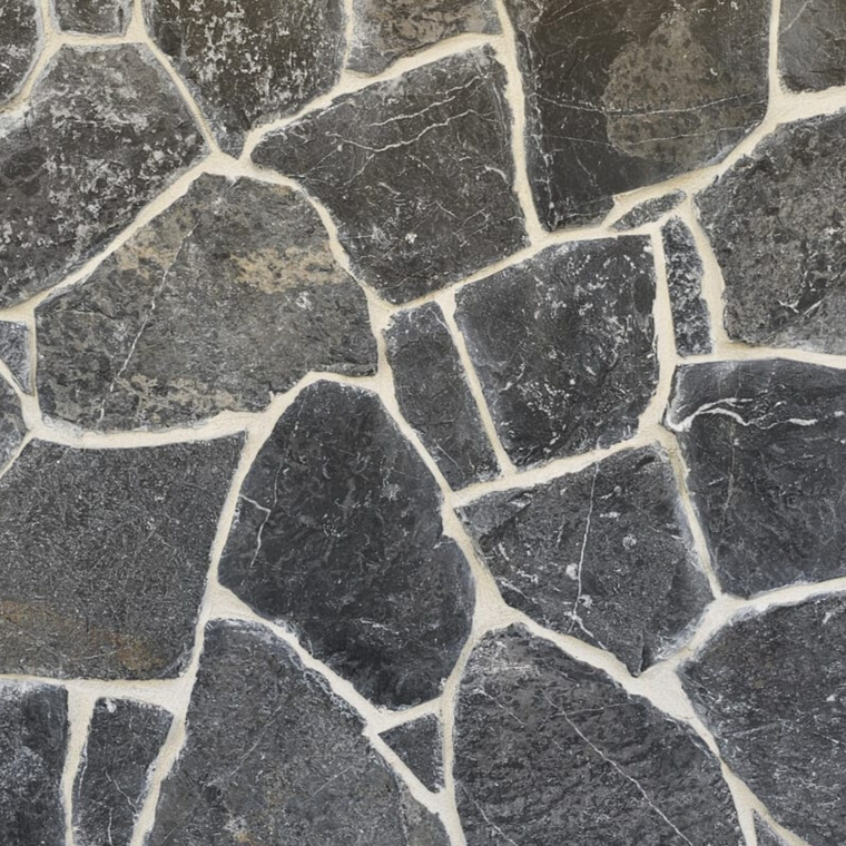 A close-up of Celestia Stone Cladding shows large, dark gray stones with white mortar in between. The free style design uses stones of different shapes and sizes, creating an uneven, textured granite wall surface. — Stone Cladding