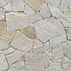 A close-up view of Sahara Stone Cladding shows an irregular arrangement of light-colored natural sandstone pieces, fitted together to create a textured, natural look reminiscent of crazy paving.