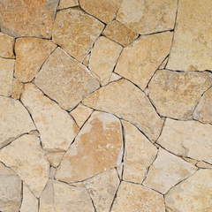 Nivara Stone Cladding features irregularly shaped, tan and beige natural limestone tiles that fit together for a rustic, textured look—ideal for creating earthy feature walls in landscape projects.