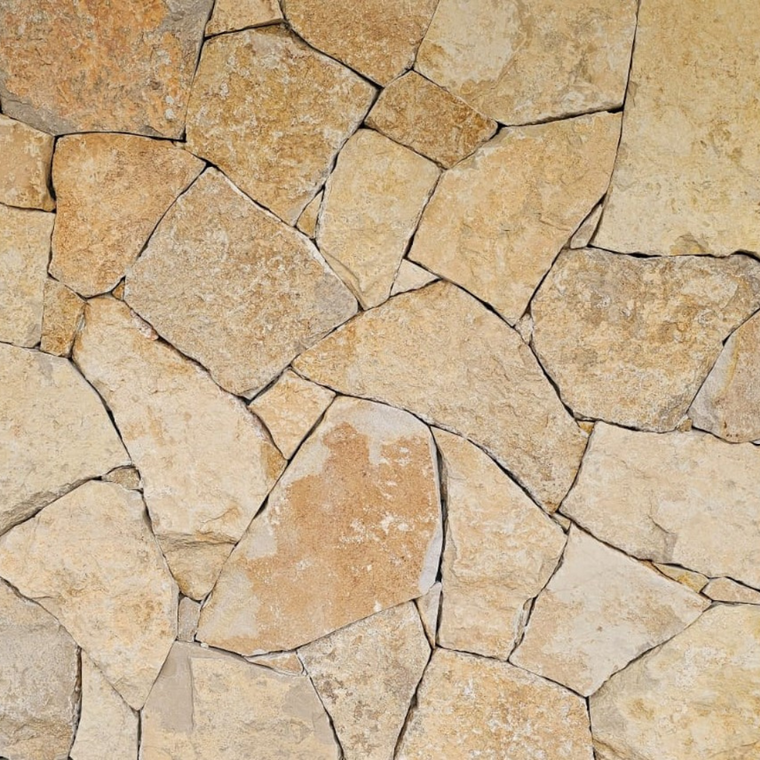 Nivara Stone Cladding features irregularly shaped, tan and beige natural limestone tiles that fit together for a rustic, textured look—ideal for creating earthy feature walls in landscape projects. — Stone Cladding