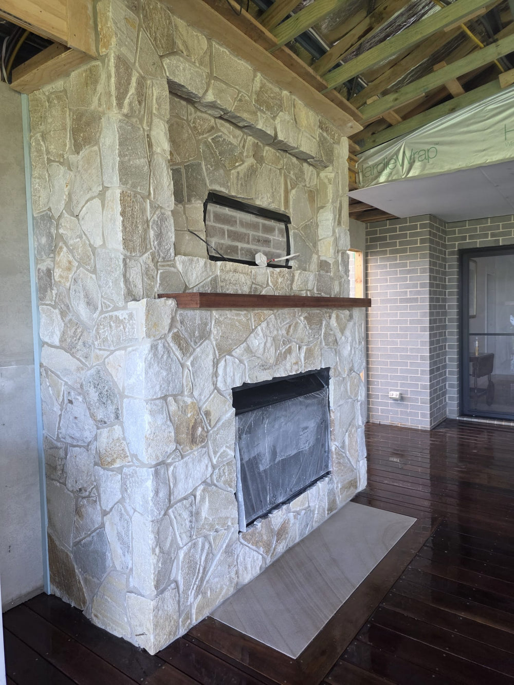A close-up of a Cresta Beige Stone Cladding wall displays variously shaped, light brown and beige stones with visible gaps and seams, highlighting the freestyle walling technique.